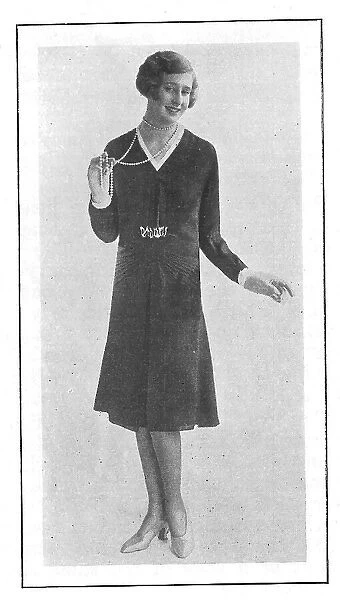 Model wearing a short-skirted afternoon frock and a string of pearl beads Date: 1930