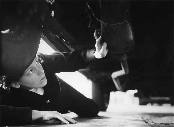 Woman police officer checking under a car, London