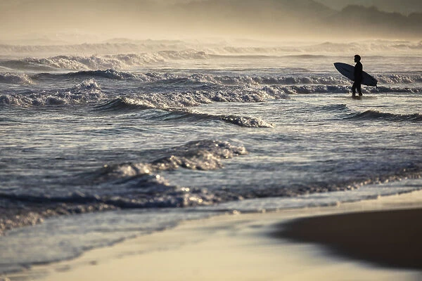 A surfer observes sea at Playa del Puntal, Santander, Cantabria, Spain