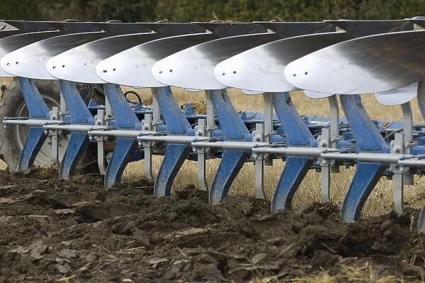 Close-up of eight furrow reversible plough, ploughing stubble field, Sweden, autumn