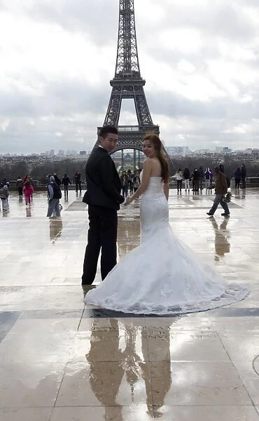 A Chinese maried couple poses in front of the Eiffel tower on February 25, 2014, in Paris
