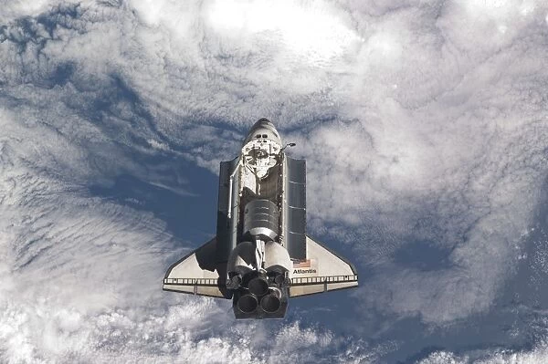 Space shuttle Atlantis above a cloud covered Earth