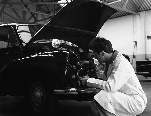 Auto electrician changing a light bulb on a Morris Minor, Nottingham, Nottinghamshire, 1961