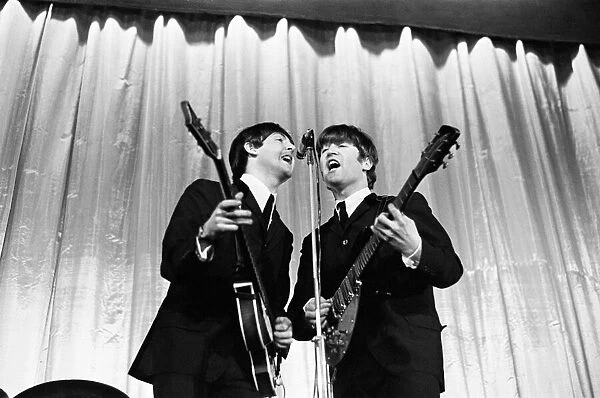 Paul McCartney and John Lennon sharing the microphone during a performance by British pop