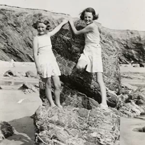 Two young girls playing on the rocks on a Cornish beach