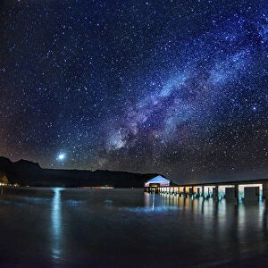 The Milky Way and Venus rise over the Hanalei Bay with the Hanalei Pier in the foreground