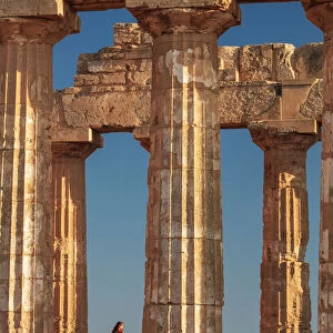 Selinunte, Sicily. A woman visiting an old Greek temple at sunset with the sea in the