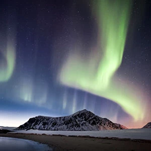 northern lights over a mountain on the beach