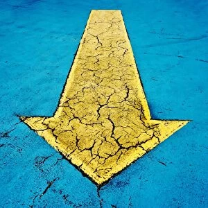 Yellow arrow on blue concrete with cracks