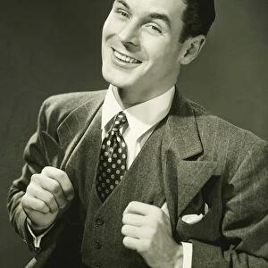Young businessman in studio smiling, (B&W), portrait