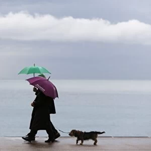 People walk on the Promenade des Anglais during a rainy afternoon, on November 25