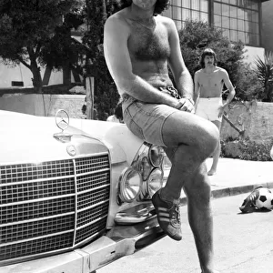 Footballer George Best poses beside his Mercedes Car June 1976