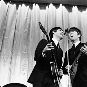 Paul McCartney and John Lennon sharing the microphone during a performance by British pop