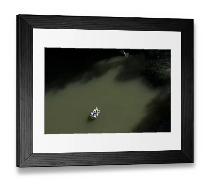 Framed Print : A Kosovo man lying in an inflatable boat takes a sunbath near a waterfall to cool