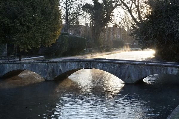 Cotswold stone bridge over River Windrush in mist, Bourton-on-the-Water, Cotswolds