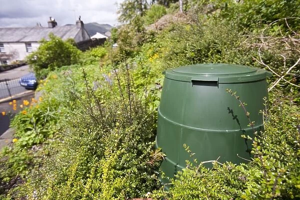 A compost bin in a garden in Ambleside, Lake District, UK. Composting your green waste prevents grennhouse gas emissions as food waste in landfill decays to emit methane, a potent greenhouse