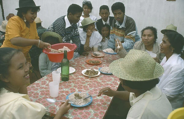 20072740. MADAGASCAR Antananarivo Large group of people having a meal of meat and rice