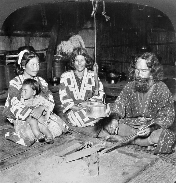 JAPAN: AINU FAMILY, c1906. An Ainu family seated around a tea kettle in their home in Hokkaido