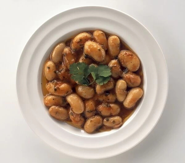 Bowl of Gigantes beans garnished with coriander leaf, a typical dish from Greece, view from above