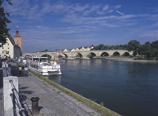 Germany, Bavaria, Regensburg, ratisbon, the picturesque Steiner Brucke, an outstanding example of medieval engineering spanning the Danube, leading to the old town of Regensburg. Passenger boats line the edge of the river