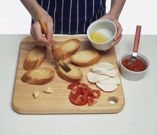 Girl basting crostini toast with olive oil on chopping board