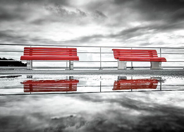 Reflection of two red benches in a puddle on La pier du Moulleau, La Teste-de-Buch, France