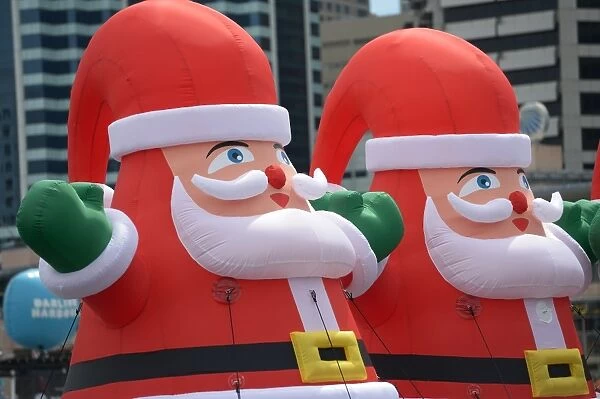 Australia-Theme. Giant inflatable Santas are displayed on a platform in