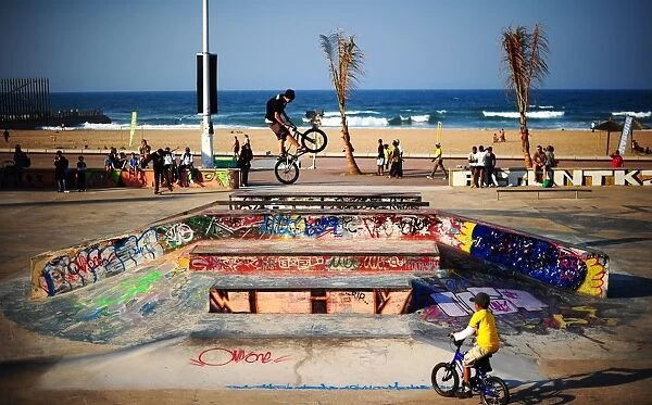 A BMX (Bicycle Motor Cross) rider performs on a ramp in a skatepark decorated with