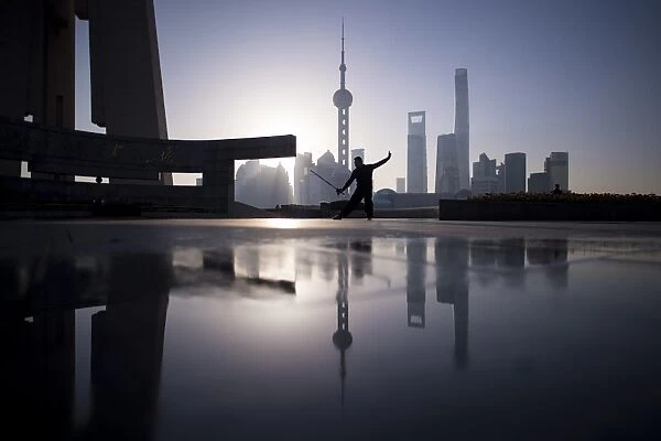 China-Society. A man practice Tai Chi with a sword during sunrise at the