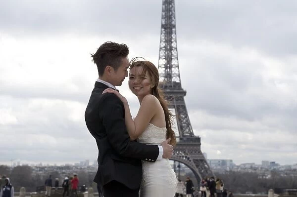 A Chinese maried couple pose in front of the Eiffel tower on February 25, 2014, in Paris