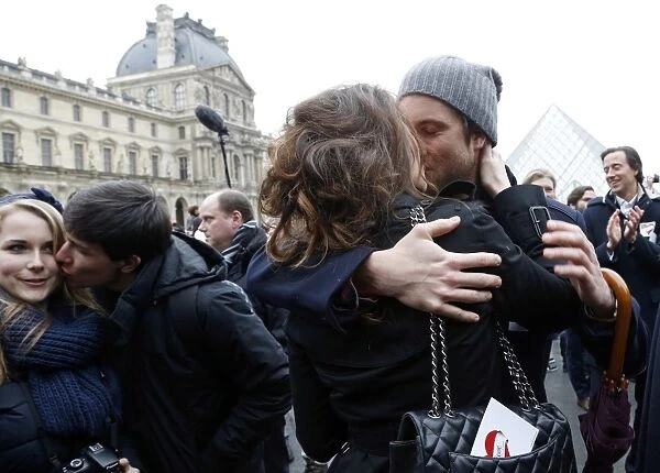 A couple kisses during a flashmob near the Louvre Pyramid in Paris on February 14