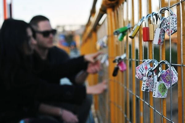 A couple looks at a love lock they attached to a bridge overlooking the