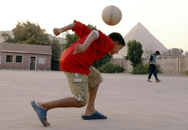 Egypt-Soccer. An Egyptian boy plays football in front of the pyramids in Giza