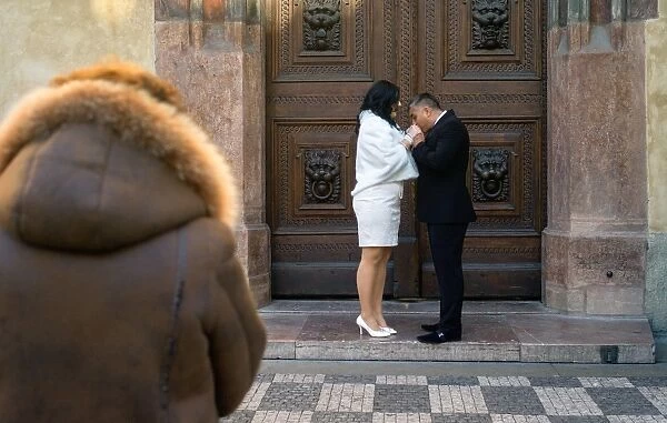 sz. An elderly women looks on as a Russian couple kiss on February 14