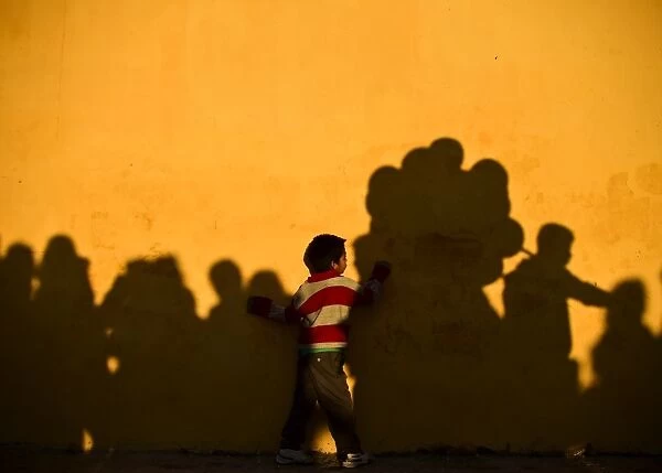 Mexico-Pope-Visit. A boy plays at sunset with shadows on the wall of the
