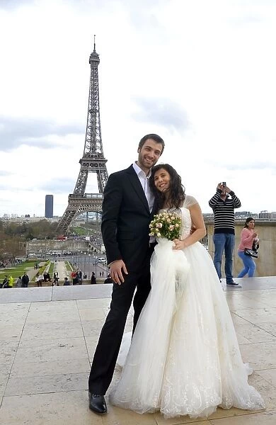 A mixed American and Roumanian newly married couple poses in front of the Eiffel tower on March 21