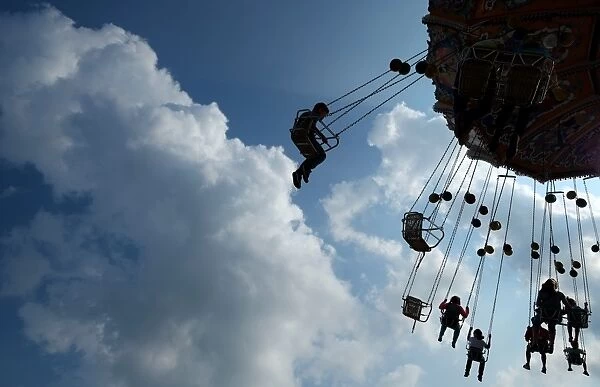 People sit on a merry-go-round at the annual funfair Cranger Kirmes in Herne