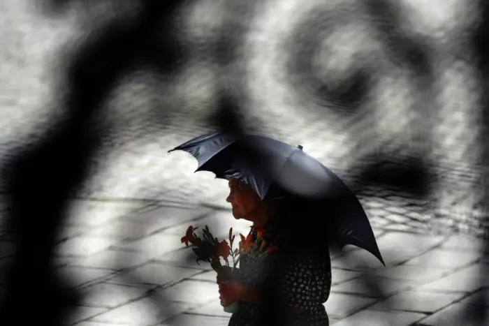 Framed Print : Photo taken through a metal gate shows an elderly woman shading herself from Framed Print : Photo taken through a metal gate shows an elderly woman shading herself from