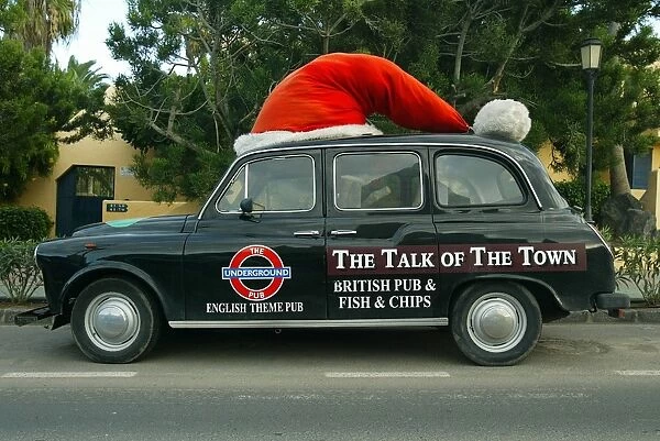 Spain_Christmas. An old London taxi wears a Santa Claus hat as it is parked