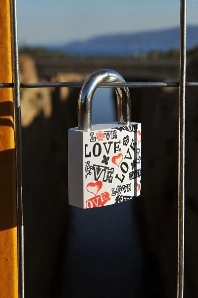 A view of a love lock attached by a couple on a bridge overlooking the