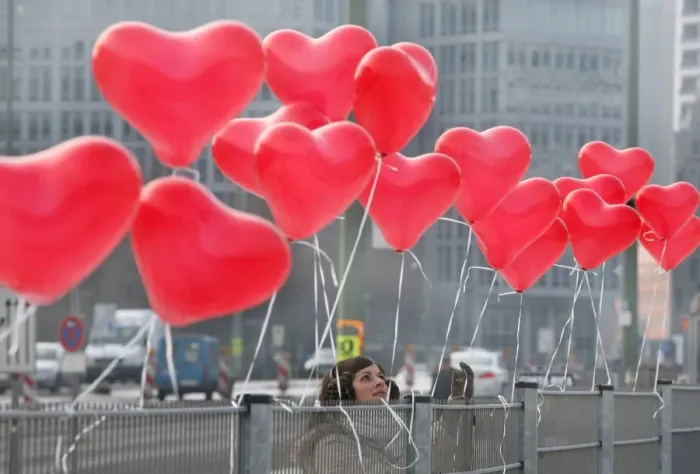 Framed Print : A woman fixes red heart-shaped balloons on a fence on Februray 14, 2012 in Berlin
