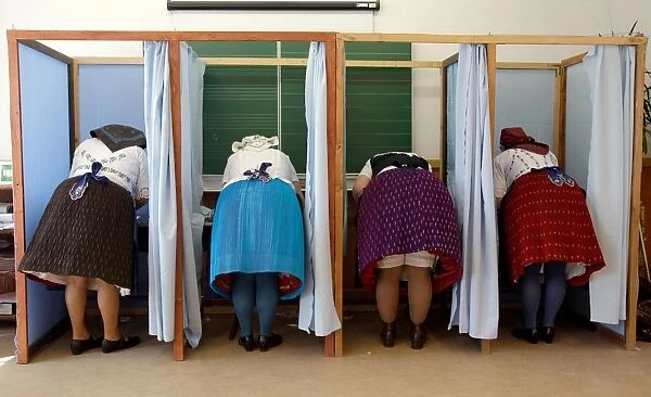 Women dressed in traditional Hungarian outfit prepare their votes in a polling station
