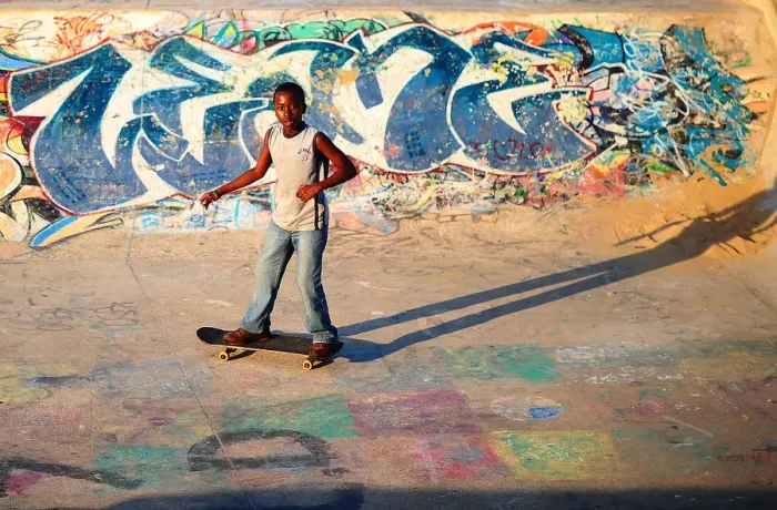 Framed Print : A young boy skateboards past a ramp decorated with graffiti in a skate park in Durban Framed Print : A young boy skateboards past a ramp decorated with graffiti in a skate park in Durban