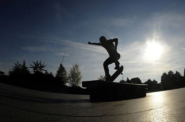 A youth performs a trick on his skateboard during a warm autumn sunny day on October 4