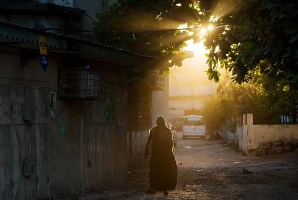 Zanzibar-Vote. A woman walks along a street as the sun sets in Stone Town