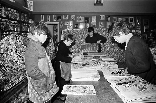 Newspaper round boys inside a newsagents, sorting the papers ready for delivery