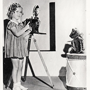 Shirley Temple photographing her teddy bear on a postcard