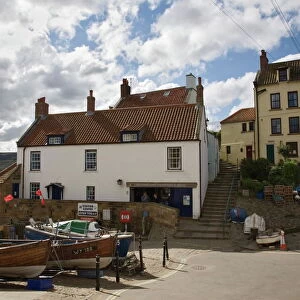 Boats in front of Old Coastguard Station Visitor Centre in The Dock and Cromwells Pub at end of Coast to Coast walk, Old Bay area, Robin Hoods Bay, Yorkshire, England, United