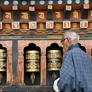 Old Bhutanese man turning prayer wheels in Buddhist temple, Thimphu, Bhutan, Asia