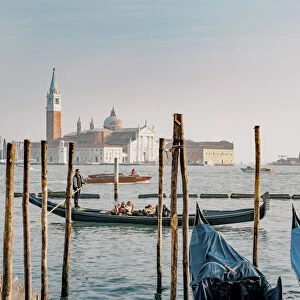 Gondola with tourists at bacino di San Marco with the island of San Giorgio Maggiore